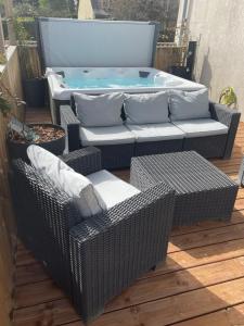 a patio with a hot tub and wicker furniture at Résidence Cosy in La Mézière