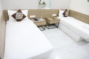 two beds in a room with a table and two beds at SwanSuites Gachibowli in Hyderabad