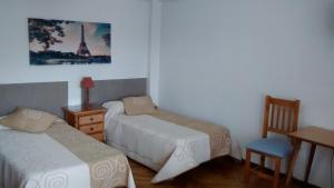 a bedroom with two beds and a table and a desk at Pension Santa Rita in Santiago de Compostela