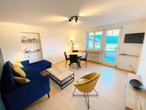 een woonkamer met een blauwe bank en een tafel bij Seeblick an Luxusmeile 4P, 70m2 - Parkplatz, - S11-1 in St. Moritz