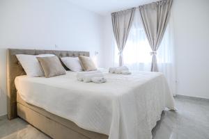 a white bedroom with a large bed with towels on it at Luxury rooms Green and Gold Split in Split