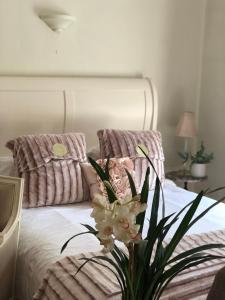 Una cama con dos almohadas y un jarrón de flores. en Lovely Studio Apartment with Roof Top Conservatory, en Goostrey