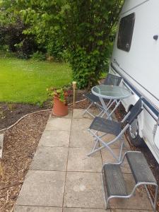 two chairs and a table next to a white van at Maes Offa Stays in Llandysilio