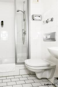 a white bathroom with a toilet and a shower at Hotel Blutenburg in Munich