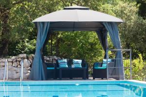 a gazebo with chairs and an umbrella next to a pool at Villa Luce Konavoka in Čilipi