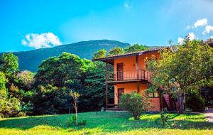an orange house with a balcony on a hill at Pousada Rosa dos Ventos Capão in Vale do Capao