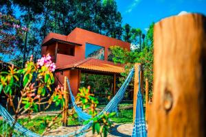 a house with a swing in front of a house at Pousada Rosa dos Ventos Capão in Vale do Capao