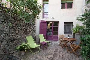 Porrera的住宿－LA CASETA DEL PRIORAT II，一个带椅子和桌子的庭院和紫色的门