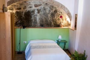 um quarto com uma cama e uma parede de pedra em LA CASETA DEL PRIORAT II em Porrera