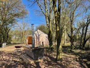a grill and a tent in a field with trees at The Warren, Hot Tub in Brackley