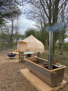 a tent and a grill with a fire hydrant in a field at The Warren, Hot Tub in Brackley