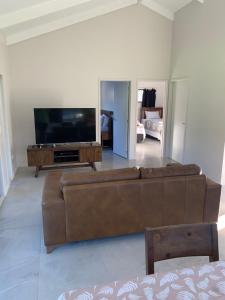 a living room with a brown couch and a flat screen tv at Kaia Villas in Rarotonga