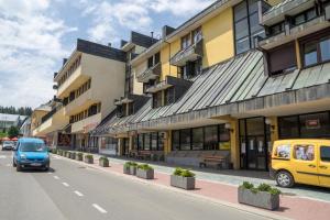 a blue van driving down a street next to a building at Lux Centre Apartment in Žabljak
