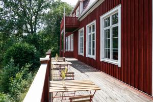 eine Terrasse mit Stühlen und Tischen in einem roten Gebäude in der Unterkunft Nordic Refuge B&B in Fröskog