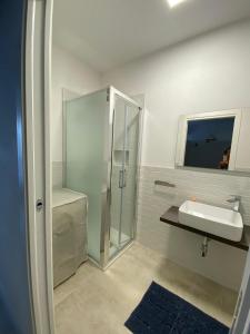 een badkamer met een glazen douche en een wastafel bij Torregrande Apartments in Torre Grande