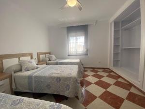 1 dormitorio con 2 camas y suelo a cuadros en Casa Silvia, en Cádiz