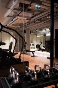 a gym with a row of exercise equipment and mirrors at You Hotels Deauville - Handwritten Collection in Deauville