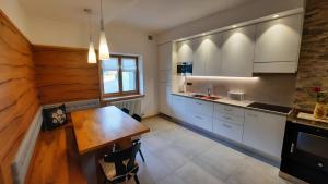a kitchen with white cabinets and a wooden table at Il giardino di Anna - Appartamento 1 in Fai della Paganella