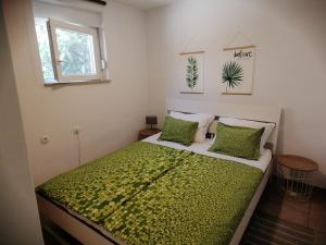 een kleine slaapkamer met een bed met groene lakens en kussens bij Small guest House Punta Pakoštane in Pakoštane