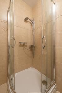 La salle de bains est pourvue d'une douche avec une porte en verre. dans l'établissement APT Nadmorskie, à Kołobrzeg
