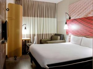 ein Hotelzimmer mit einem Bett und einem Stuhl in der Unterkunft Ibis Le Havre Sud Harfleur in Harfleur
