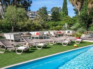 une piscine avec des chaises longues et une terrasse avec une table dans l'établissement ibis Hyeres Centre, à Hyères