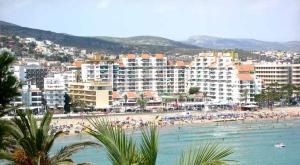 a beach with a bunch of people in the water at PeñiscolaPlaya Orangecosta in Peniscola