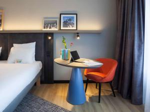 ein Hotelzimmer mit einem Bett und einem Tisch mit einem Laptop in der Unterkunft ibis Styles Den Haag Scheveningen in Scheveningen