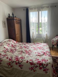 Un dormitorio con una cama con flores rojas. en SOUS LE TILLEUL CENTENAIRE, en La Tour-dʼAigues