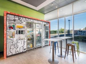 a restaurant with a refrigerator and tables and windows at ibis budget Calama in Calama