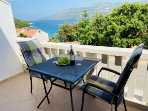 - une table bleue avec une bouteille de vin sur un balcon dans l'établissement Apartments Tri Žala, à Korčula