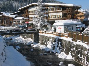 a snow covered river in front of a lodge at Appartements Robert - Hotel Bechlwirt in Kirchberg in Tirol