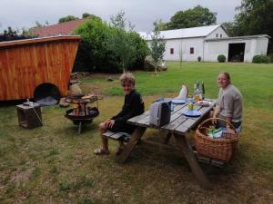 Un homme et un garçon assis à une table de pique-nique dans l'établissement Shelter Slotsgaarden, à Jels