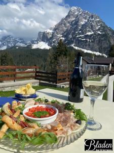 a table with a plate of food and a glass of wine at Wellness Hotel Bladen in Sappada