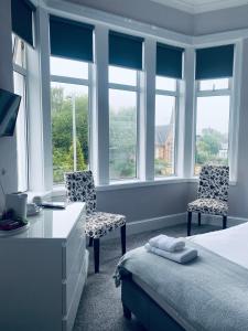 Schlafzimmer mit 2 Stühlen, einem Bett und Fenstern in der Unterkunft The Portmann Hotel in Kilmarnock