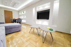 uma sala de estar com um sofá, uma mesa e uma televisão em Argo Suite em Piraeus