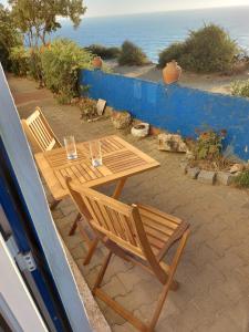 - deux chaises en bois et une table avec vue sur l'océan dans l'établissement CASA DA LAGINHA, à Zambujeira do Mar