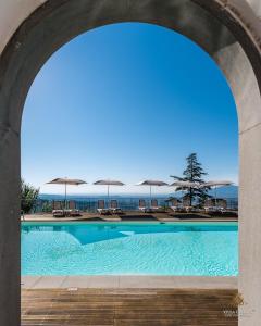 a swimming pool under an arch with chairs and umbrellas at Villa Guinigi Dimora di Epoca Exclusive Residence & Pool in Lucca