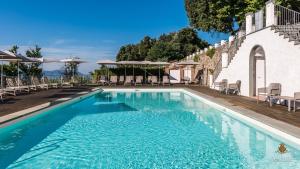 una piscina con sedie e ombrelloni accanto a un edificio di Villa Guinigi Dimora di Epoca Exclusive Residence & Pool a Lucca