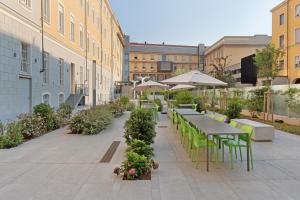 un patio esterno con tavoli, sedie e ombrelloni di Camplus Guest Bernini Casa per Ferie a Torino