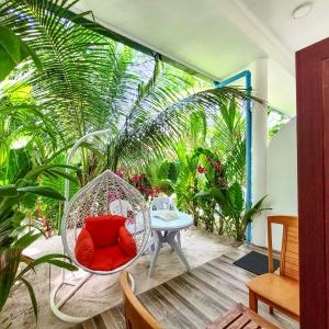 a porch with a swing and a table and plants at Sunrise Inn in Thoddoo