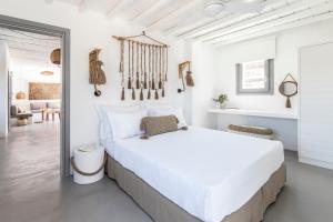 ein weißes Schlafzimmer mit einem Bett und ein Wohnzimmer in der Unterkunft Nesea Sifnos - Luxury Residences in Platis Gialos Sifnos