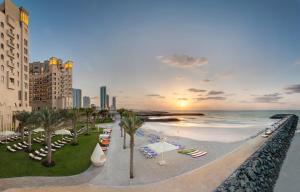 a beach with chairs and umbrellas and the ocean at Bahi Ajman Palace Hotel in Ajman 