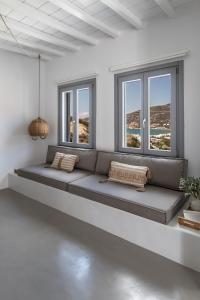 Nesea Sifnos - Luxury Residences في بلاتيس ييالوس سيفنوس: أريكة كبيرة في غرفة بيضاء مع نوافذ