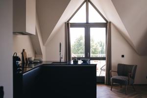 a kitchen with a large window and a black counter at Dudok Studio's Arnhem-Oosterbeek in Oosterbeek