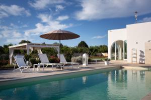 a pool with chairs and an umbrella next to a house at Lamia Petricore Ostuni in Ostuni
