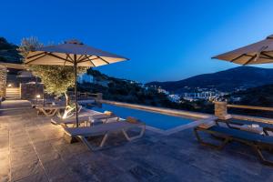 a pool with tables and umbrellas on a roof at Nesea Sifnos - Luxury Residences in Platis Gialos