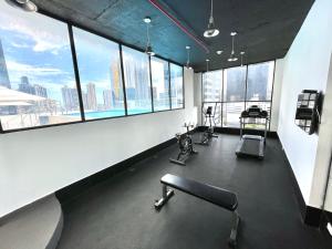 een kantoor met ramen en een fitnessruimte met fitnessapparatuur bij Hotel Mio Panamá in Panama-Stad