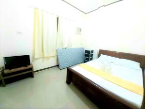 a bedroom with a bed and a television in it at Gaea's Apartments in Panglao