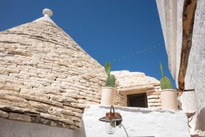 a building with a stone roof with cacti on it at Trulli Magheia in Alberobello
